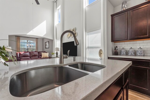 kitchen with a wealth of natural light, sink, light stone countertops, and backsplash