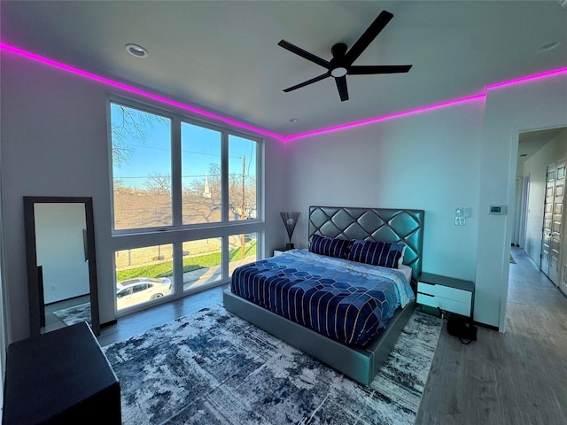 bedroom featuring a wall of windows, wood-type flooring, ceiling fan, and baseboard heating