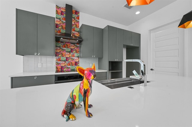 kitchen featuring wall oven, gray cabinetry, wall chimney exhaust hood, and sink