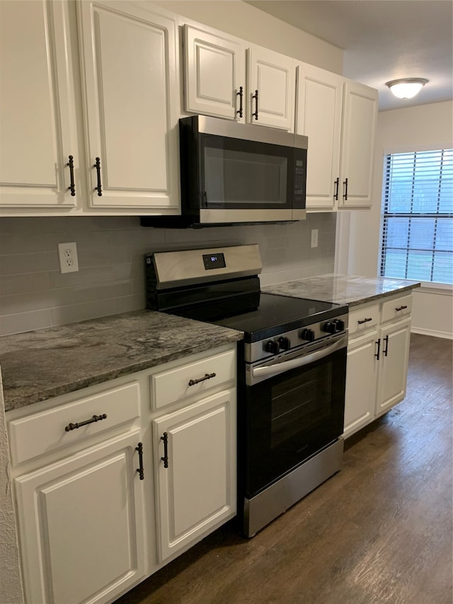 kitchen featuring tasteful backsplash, dark hardwood / wood-style flooring, white cabinetry, stainless steel appliances, and dark stone counters