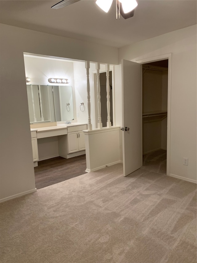 unfurnished bedroom featuring built in desk, ceiling fan, light carpet, and a closet