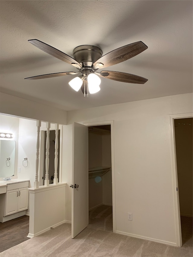 unfurnished bedroom with a spacious closet, a closet, ceiling fan, connected bathroom, and light colored carpet