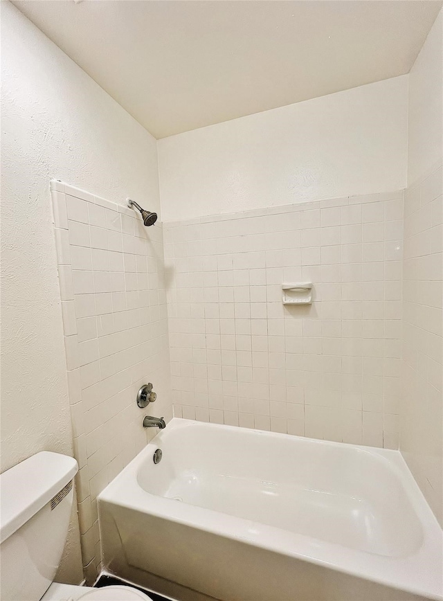 bathroom with toilet and tiled shower / bath