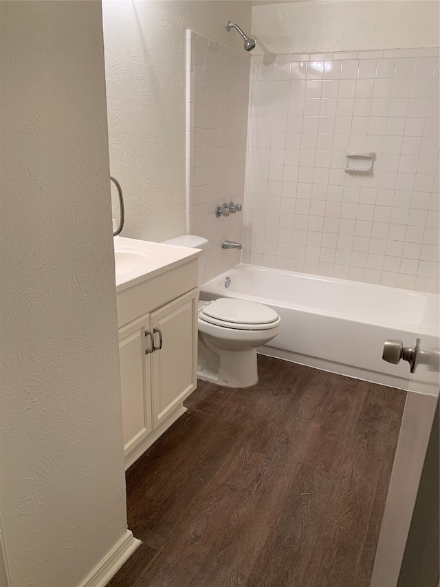 full bathroom with tiled shower / bath, vanity, hardwood / wood-style flooring, and toilet