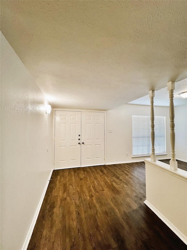 interior space with a textured ceiling and dark hardwood / wood-style floors