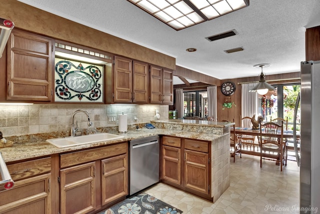 kitchen featuring pendant lighting, sink, a textured ceiling, kitchen peninsula, and stainless steel appliances