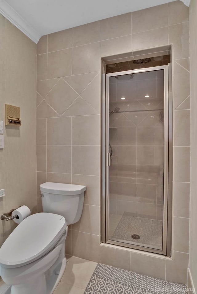 bathroom featuring ornamental molding, a shower with door, tile walls, tile patterned flooring, and toilet