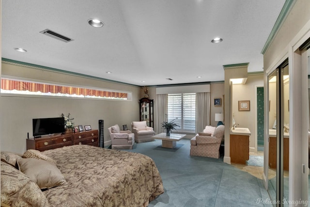 carpeted bedroom with a textured ceiling, ensuite bath, and crown molding