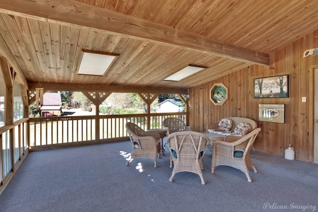 dining area with carpet flooring, lofted ceiling with skylight, wood ceiling, and wood walls