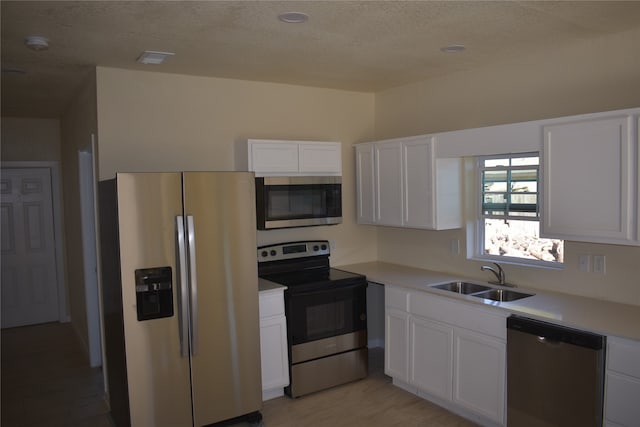 kitchen featuring sink, a textured ceiling, stainless steel appliances, white cabinets, and light hardwood / wood-style flooring