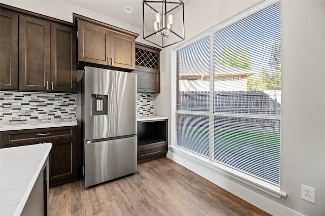 kitchen with decorative backsplash, dark brown cabinets, light wood-type flooring, pendant lighting, and stainless steel refrigerator with ice dispenser