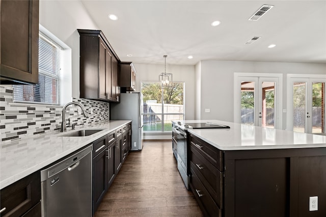 kitchen featuring sink, a center island, stainless steel appliances, pendant lighting, and dark wood-type flooring