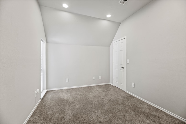 spare room with lofted ceiling and dark colored carpet