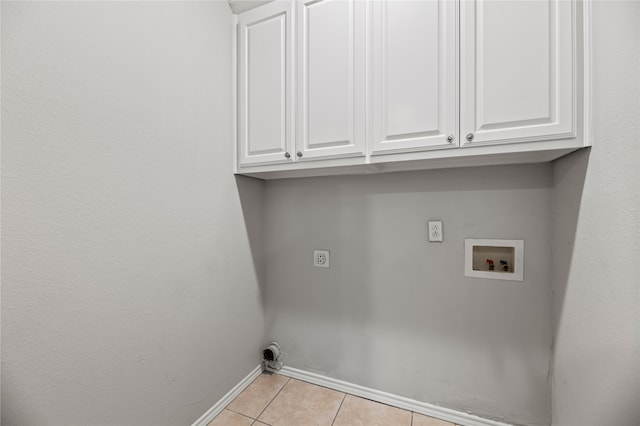 laundry room with hookup for an electric dryer, hookup for a washing machine, light tile patterned floors, and cabinets