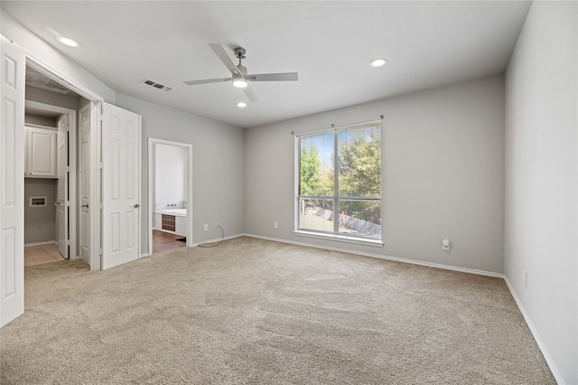 unfurnished bedroom featuring light carpet, ceiling fan, and ensuite bath