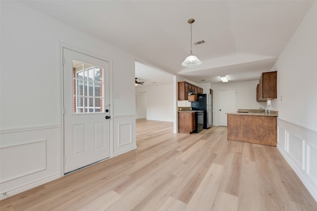 kitchen with kitchen peninsula, black range with electric stovetop, light wood-type flooring, and stainless steel fridge