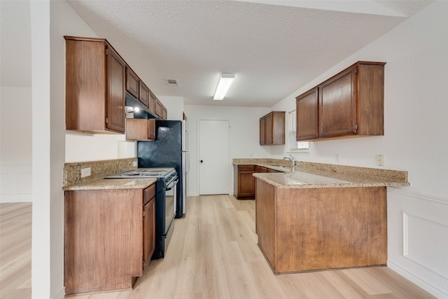 kitchen featuring light hardwood / wood-style floors, range with electric cooktop, a textured ceiling, and sink