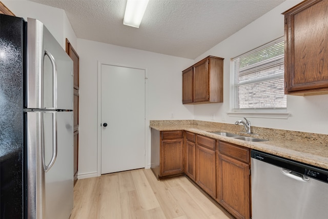 kitchen featuring sink, a textured ceiling, appliances with stainless steel finishes, and light hardwood / wood-style flooring