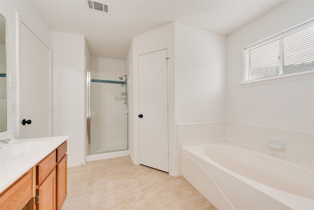 bathroom featuring vanity, a textured ceiling, tile patterned floors, and separate shower and tub