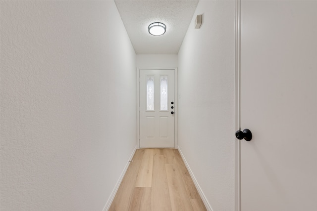 doorway to outside with light hardwood / wood-style flooring and a textured ceiling