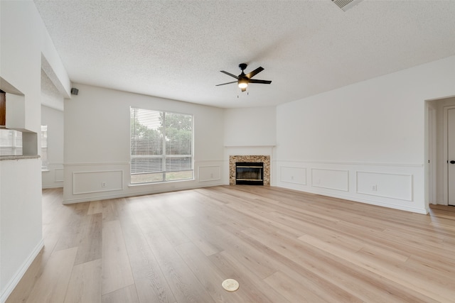 unfurnished living room with light hardwood / wood-style flooring, a textured ceiling, and ceiling fan