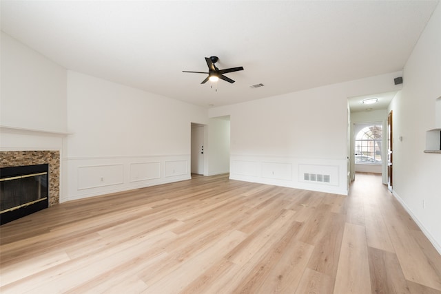 unfurnished living room featuring a fireplace, light wood-type flooring, and ceiling fan