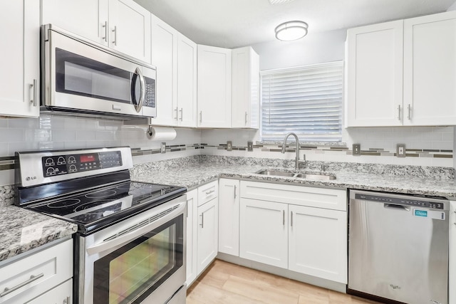 kitchen featuring light stone counters, white cabinetry, sink, and appliances with stainless steel finishes