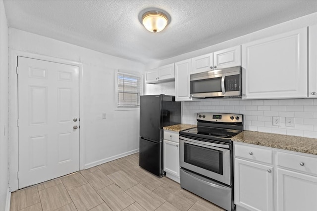 kitchen with a textured ceiling, white cabinetry, stainless steel appliances, light stone counters, and decorative backsplash