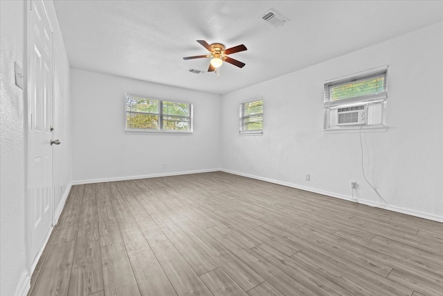 spare room with cooling unit, light wood-type flooring, and ceiling fan