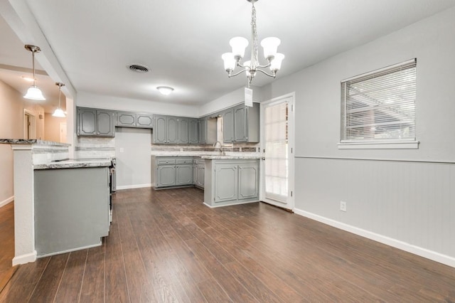 kitchen featuring a notable chandelier, gray cabinets, sink, hanging light fixtures, and dark hardwood / wood-style flooring