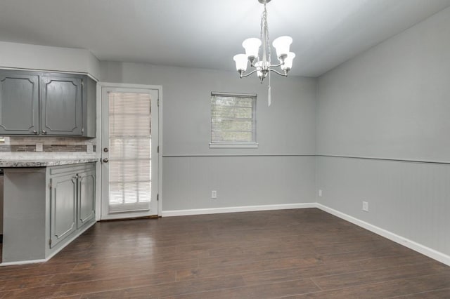 unfurnished dining area featuring dark wood-type flooring and a notable chandelier