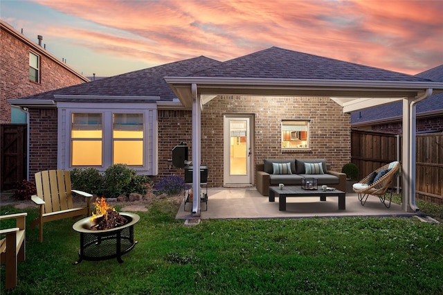 back house at dusk with a lawn, an outdoor living space with a fire pit, and a patio area