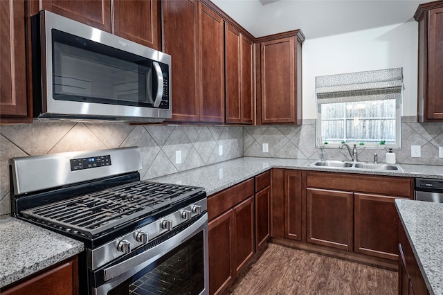 kitchen with light stone countertops, appliances with stainless steel finishes, decorative backsplash, and sink