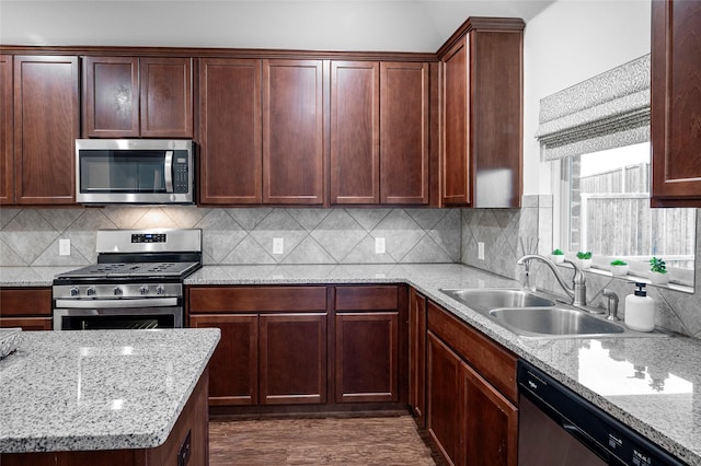 kitchen with tasteful backsplash, sink, light stone countertops, stainless steel appliances, and dark hardwood / wood-style flooring