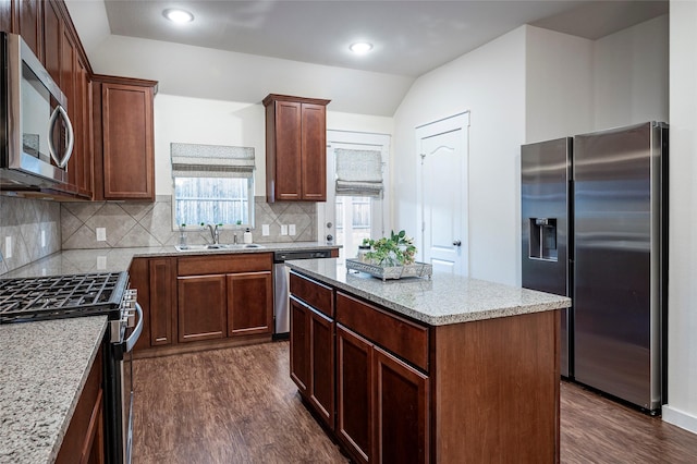 kitchen featuring appliances with stainless steel finishes, a center island, dark hardwood / wood-style flooring, sink, and light stone counters