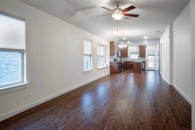 2418 San Marcos Dr, Forney, TX 75126 - unfurnished living room featuring a wealth of natural light, dark wood-type flooring, visible vents, and ceiling fan with notable chandelier