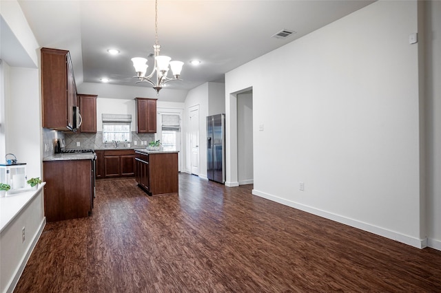 kitchen with decorative light fixtures, a kitchen island, an inviting chandelier, appliances with stainless steel finishes, and dark hardwood / wood-style flooring