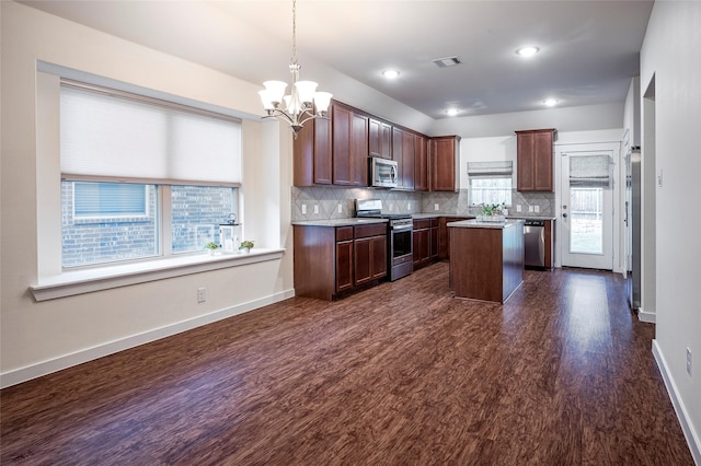 2418 San Marcos Dr, Forney, TX 75126 - kitchen featuring dark wood-type flooring, a kitchen island, a chandelier, tasteful backsplash, and appliances with stainless steel finishes