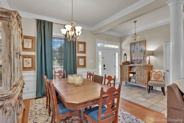 dining area featuring an inviting chandelier, light wood-type flooring, crown molding, and ornate columns