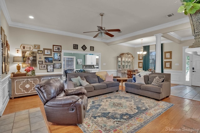 living room featuring ceiling fan with notable chandelier, light hardwood / wood-style floors, ornate columns, and crown molding