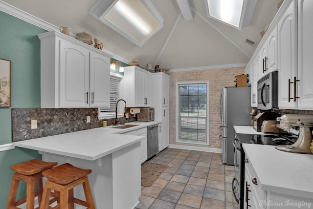 kitchen featuring white cabinetry, sink, a kitchen breakfast bar, vaulted ceiling with beams, and appliances with stainless steel finishes