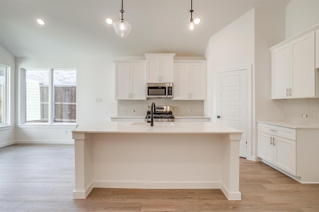 kitchen featuring pendant lighting, light hardwood / wood-style flooring, stainless steel appliances, and white cabinets