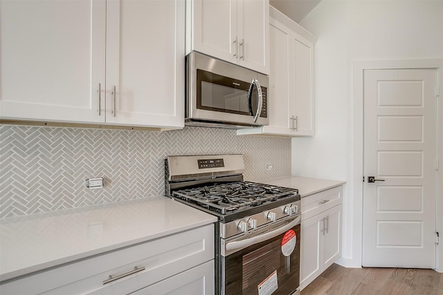 kitchen featuring appliances with stainless steel finishes, white cabinets, tasteful backsplash, and light hardwood / wood-style floors