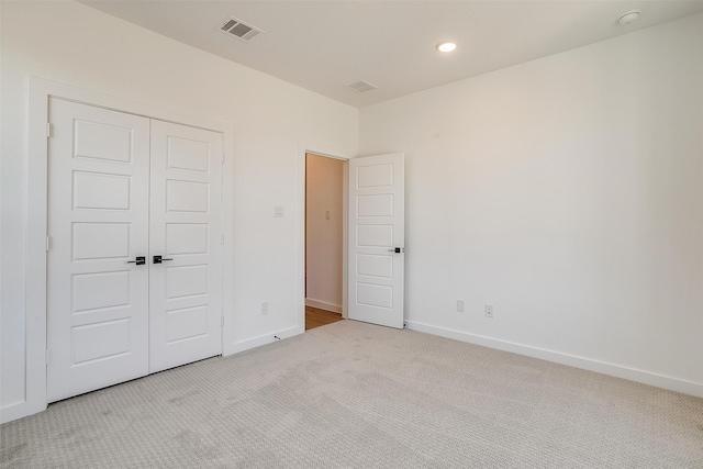 unfurnished bedroom featuring a closet and light colored carpet