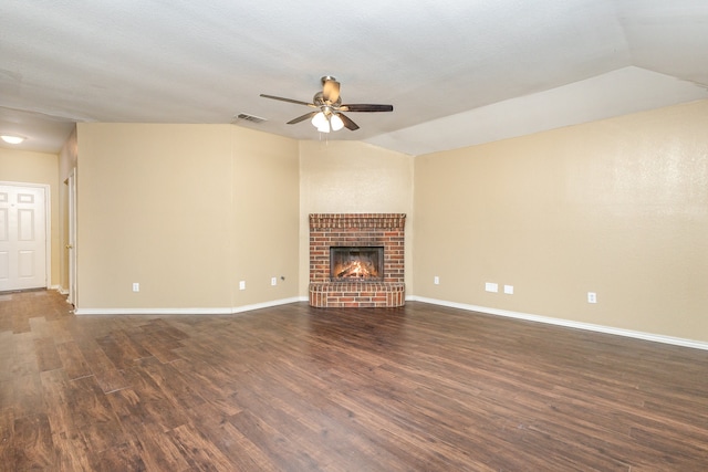 unfurnished living room with ceiling fan, lofted ceiling, a brick fireplace, and dark hardwood / wood-style floors