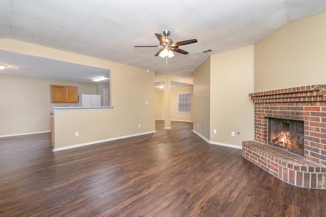 unfurnished living room featuring dark wood-type flooring, vaulted ceiling, a brick fireplace, a textured ceiling, and ceiling fan