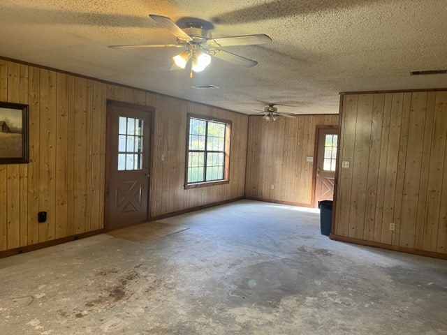 unfurnished room featuring ceiling fan, a textured ceiling, ornamental molding, and wooden walls