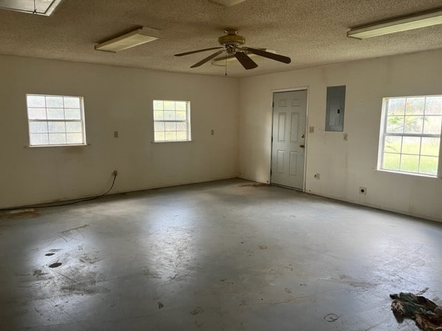 unfurnished room with a wealth of natural light, electric panel, and ceiling fan