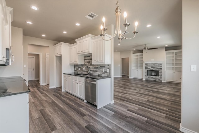 kitchen with white cabinets, ceiling fan, stainless steel dishwasher, dark wood-type flooring, and a fireplace