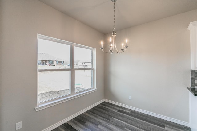 unfurnished dining area featuring an inviting chandelier and dark hardwood / wood-style flooring